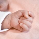 A new version of birth and death certificates features English-language data and a QR code - hand of a baby