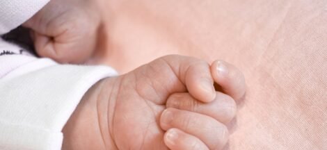 A new version of birth and death certificates features English-language data and a QR code - hand of a baby