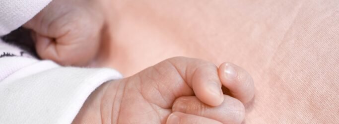 A new version of birth and death certificates features English-language data and a QR code - hand of a baby