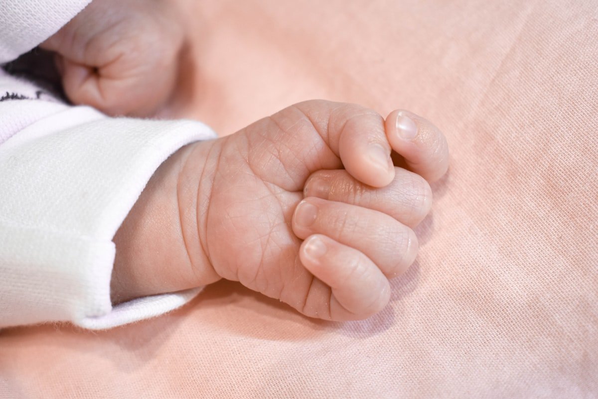 A new version of birth and death certificates features English-language data and a QR code - hand of a baby
